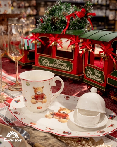 Décoration de table de Noël avec train miniature et vaisselle ours en peluche.